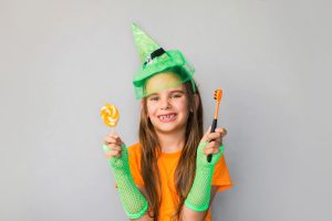 young girl holding candy and a tooth brush in a halloween costume