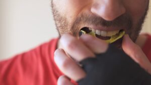 Man preparing to fit a yellow sports mouthguard, emphasizing the importance of dental protection during athletic activities.